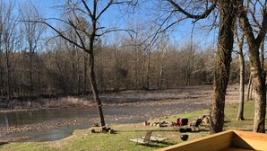 A wooden deck with a bench and a table, overlooking a river and trees. - Liberty Cabin on Collier creek!! In Caddo Gap (Norman)