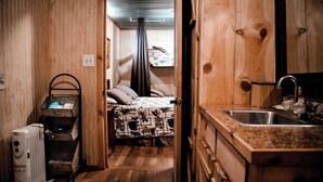A compact room with a bed, a radiator, a sink, and a wooden door. - Liberty Cabin on Collier creek!! In Caddo Gap (Norman)