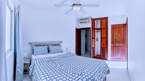 A bedroom with a bed, a ceiling fan, and wooden doors.