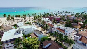 A coastal town with beachfront properties, a beach with umbrellas, and a clear view of the ocean.