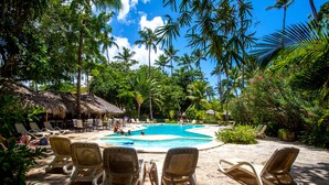 A pool area with lounge chairs and a thatched-roof structure.