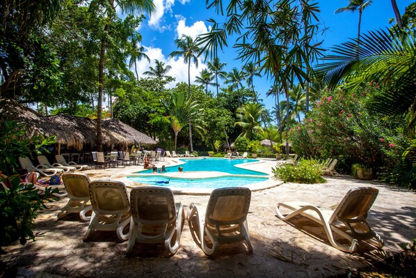 A pool area with lounge chairs and a thatched-roof structure. - Los Corales Beach Village - Your private paradise - 2BR first floor - LT#A2 (Bávaro)