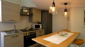 A modern kitchen with wooden cabinets, stainless steel appliances, and pendant lighting. - VILLA ROSA - Apartment n. 2 "GIGLIO" (4 beds): (Napoli)
