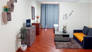 Een woonkamer met een bank, een salontafel, een televisie, een dressoir en een kamerplant.
