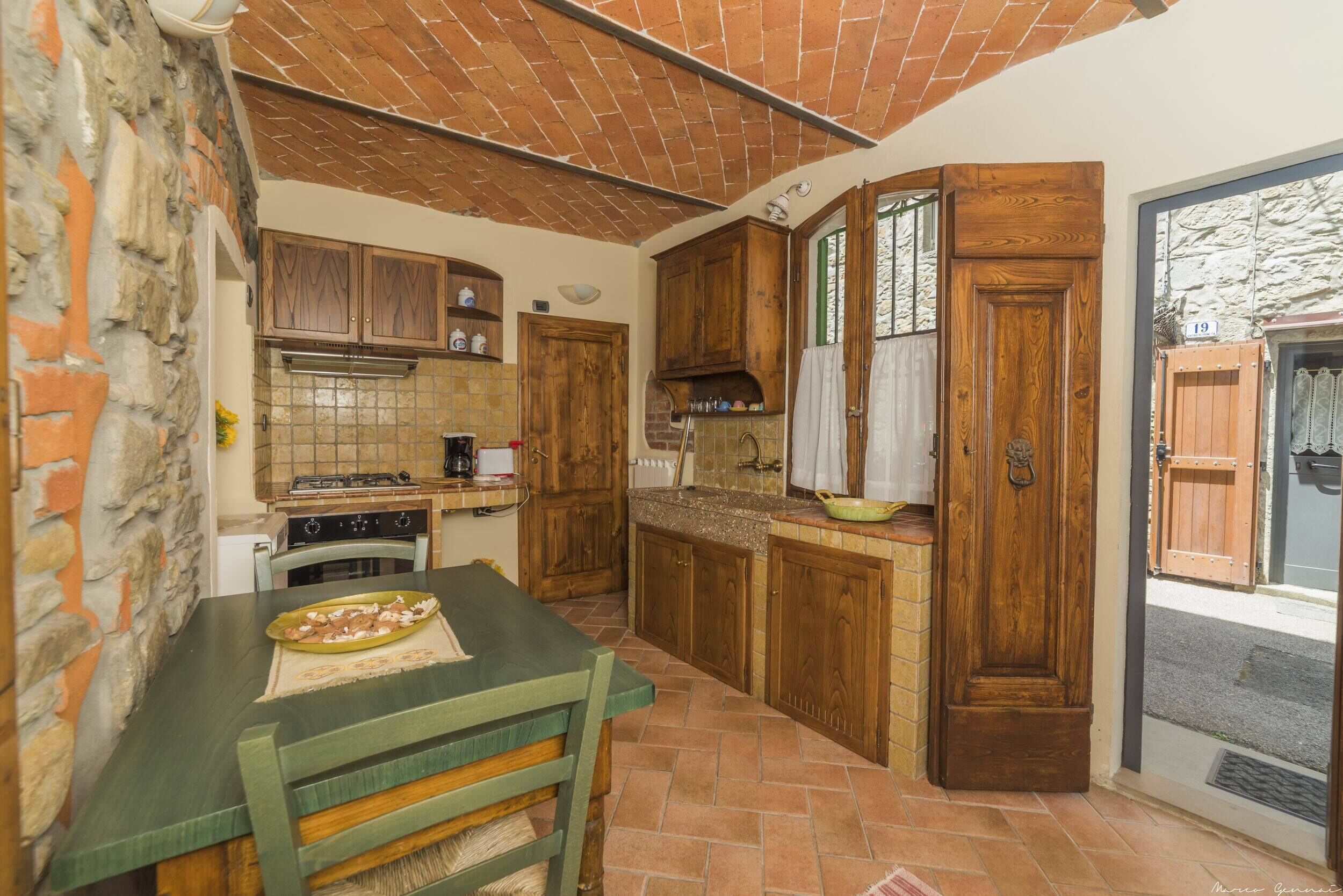 A kitchen with wooden cabinets, a dining table, and a stone wall.