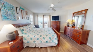 A bedroom with a bed, wooden dresser, and a ceiling fan. - Spacious w/ Fantastic Views, Large Balcony, Walkable Location! (Tybee Island)