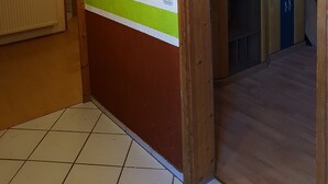 Un passadís amb un marc de porta de fusta, un radiador i una franja verda a la paret.