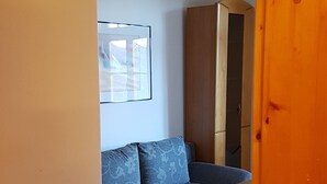 Una habitació amb un sofà blau, un armari de fusta i una taula rodona petita.