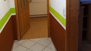 Passadís estret amb terra de rajola, porta de fusta i radiador.