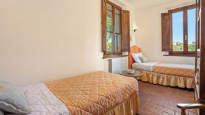 Quarto com duas camas, uma janela e um radiador.