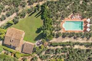 Vue aérienne d’une propriété dotée d’une piscine, d’un court de tennis et d’un bâtiment dont le toit est recouvert de tuiles.