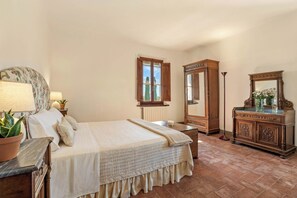 Een slaapkamer met een bed, een dressoir, een spiegel en een raam.