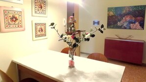 A dining area with a marble table, chairs, a vase with flowers, and framed artwork on the walls. - CA'LAMBRUSCO App. CRI (4 + 2 PEOPLE) (Smirra di cagli)
