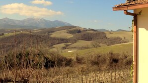 A rural landscape with rolling hills, a clear sky, and a building with a tiled roof. - CA'LAMBRUSCO App. CRI (4 + 2 PEOPLE) (Smirra di cagli)