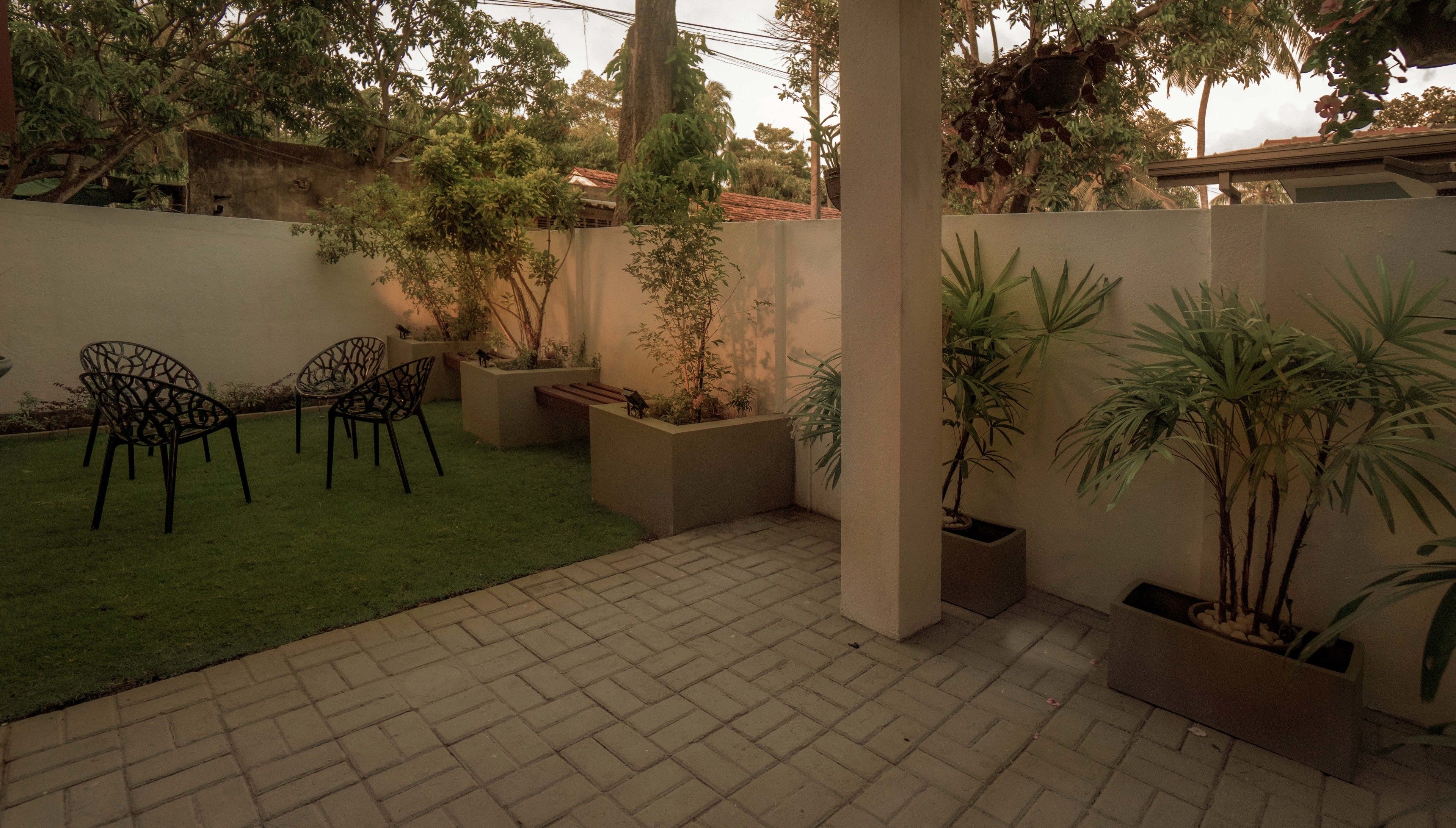 Eine Terrasse mit gefliestem Boden, einem Rasen und mehreren Blumentöpfen.