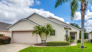 A single-story house with a garage, a well-maintained lawn, and a palm tree.
