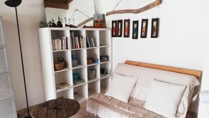 Een gezellige kamer met een houten bed, een witte boekenkast en een ronde houten tafel.