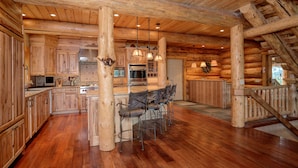 Una cocina amplia con armarios de madera, una isla central con taburetes y electrodomésticos modernos.