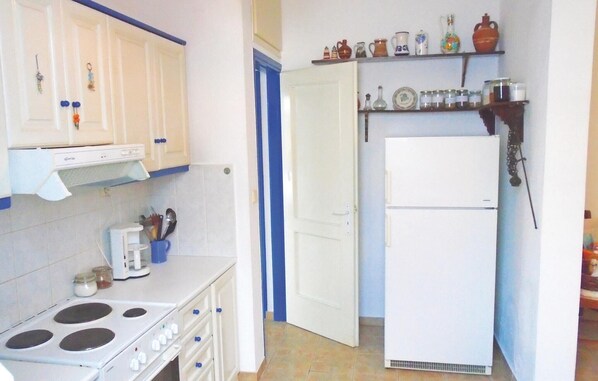 A compact kitchen with a stove, refrigerator, and various kitchen utensils. - 3 bedroom awesome apartment in Panormos (Panormos)