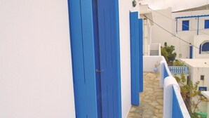 Un estrecho callejón empedrado flanqueado por edificios blancos con puertas y barandillas azules.