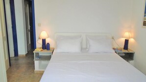 Una habitación de hotel con una cama individual, dos mesitas de noche y dos lámparas.