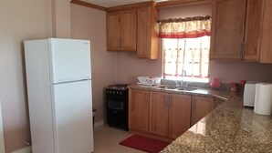 Una cocina con armarios de madera, un refrigerador blanco, una estufa a gas y un fregadero.
