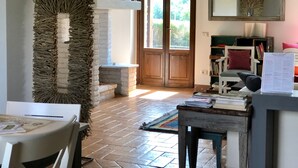 A cozy room with a brick fireplace, a wooden door, and a bookshelf with books and decorative items. - Desiderio, luxury home with pool AC, WIFI and cook school - A Fontanaro Property (Paciano)
