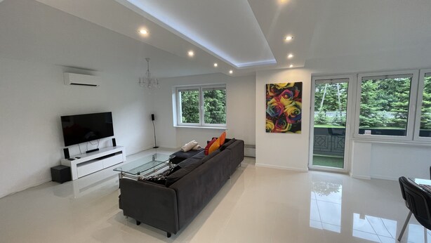 Een moderne woonkamer met een flatscreen televisie, een bank en een groot raam.