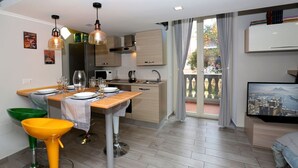 Une cuisine moderne avec un coin repas, un téléviseur et un balcon offrant une vue sur la ville.