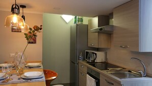 Une cuisine de taille réduite équipée d’un réfrigérateur, d’un four à micro-ondes, d’un évier et de meubles de rangement en bois.