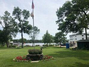 Enjoy a serene outdoor space with a lawn, flagpole, and planter, surrounded by a body of water and a building.