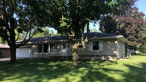 Ein eingeschossiges Haus mit verdeckter Veranda, Garage und gepflegtem Rasen.