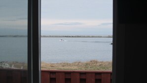 A view of a calm body of water with a distant shoreline and a boat. - Robbins by the Sea Rental - Robbins by the Sea 2 unit (Bonavista)