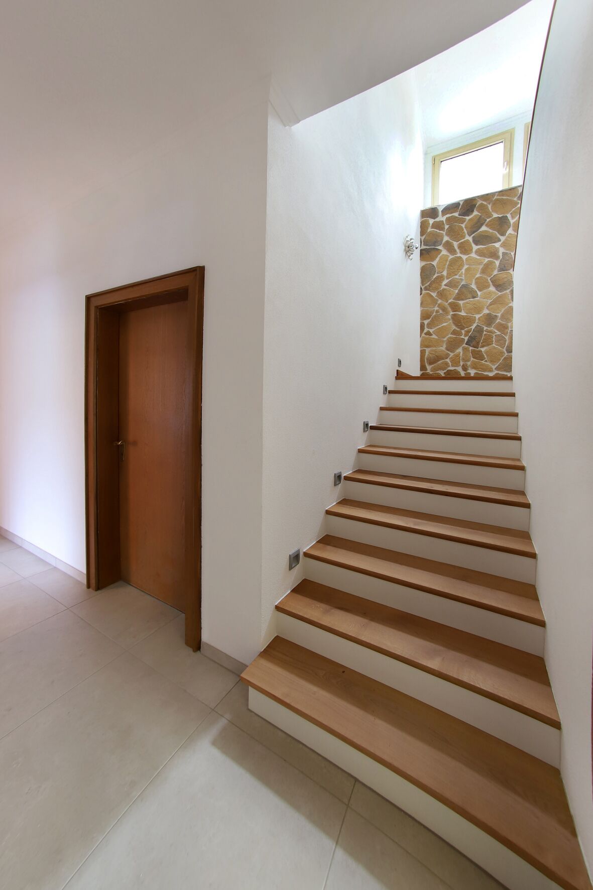 A staircase with wooden steps leading to a stone wall.
