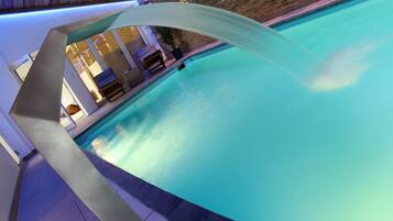 Relax by the serene pool surrounded by a curved water feature and a stone wall.