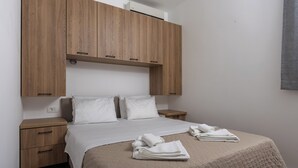 A bedroom with a bed, wooden wardrobe, bedside tables, and a wall-mounted air conditioner. - Apartments My Przno - Apartment with Side Sea View 4 (Przno, Budva)
