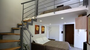 A bedroom with a bed, a sofa, a staircase, and a small table. - VILLA ROSA - Apartment n. 3 "VIOLA" (4 beds): (Napoli)