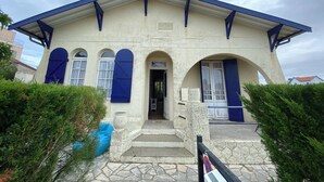 A building with a stone facade, blue shutters, and a tiled entrance. - Ref 006 - Charming Villa in the heart  of the resort (SOULAC SUR MER)