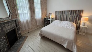 A bedroom with a bed, a dresser, a mirror, a lamp, and a fireplace. - Ref 006 - Charming Villa in the heart  of the resort (SOULAC SUR MER)