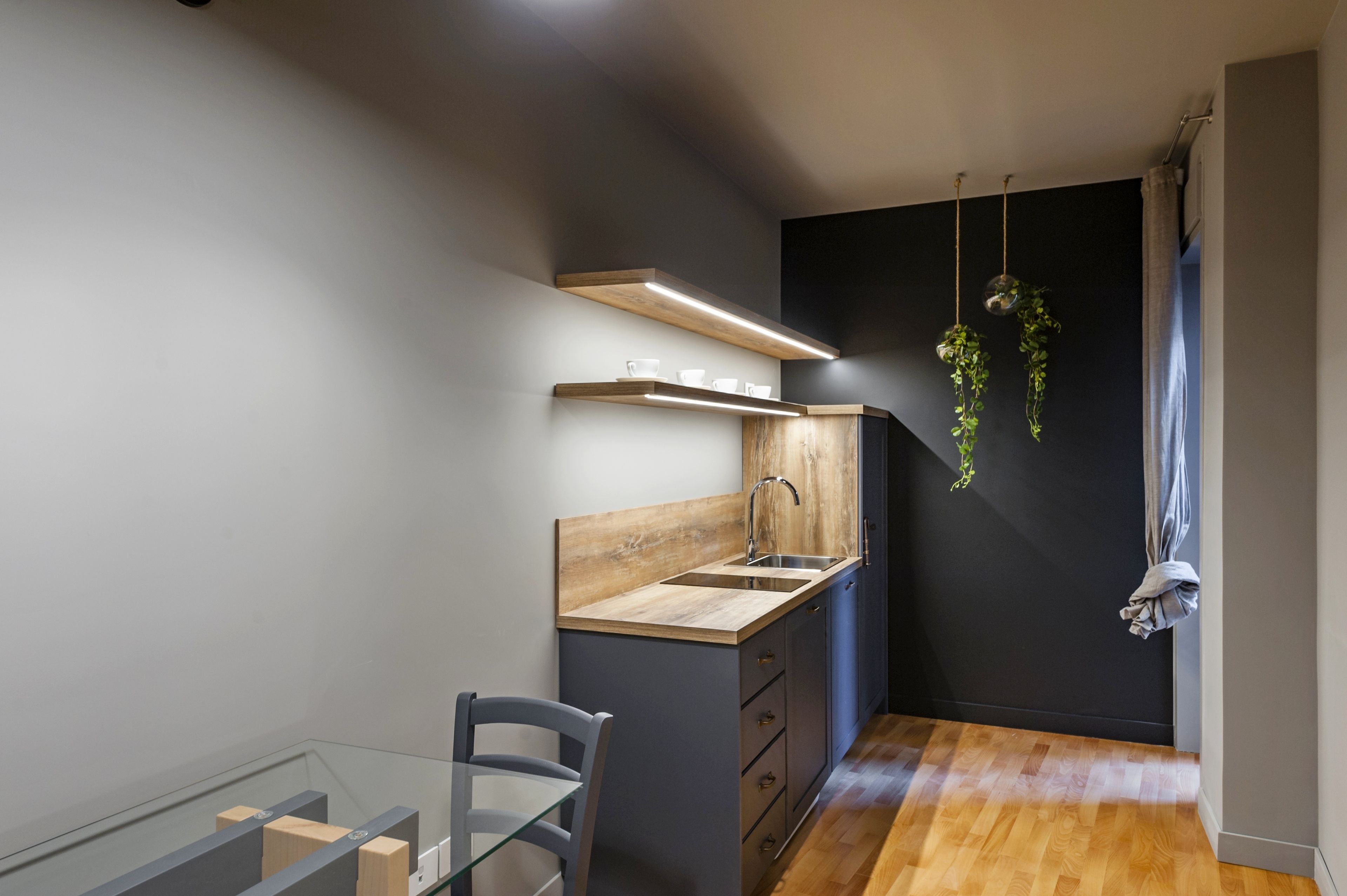 A compact kitchen with a wooden countertop, a built-in sink, and a hanging plant.
