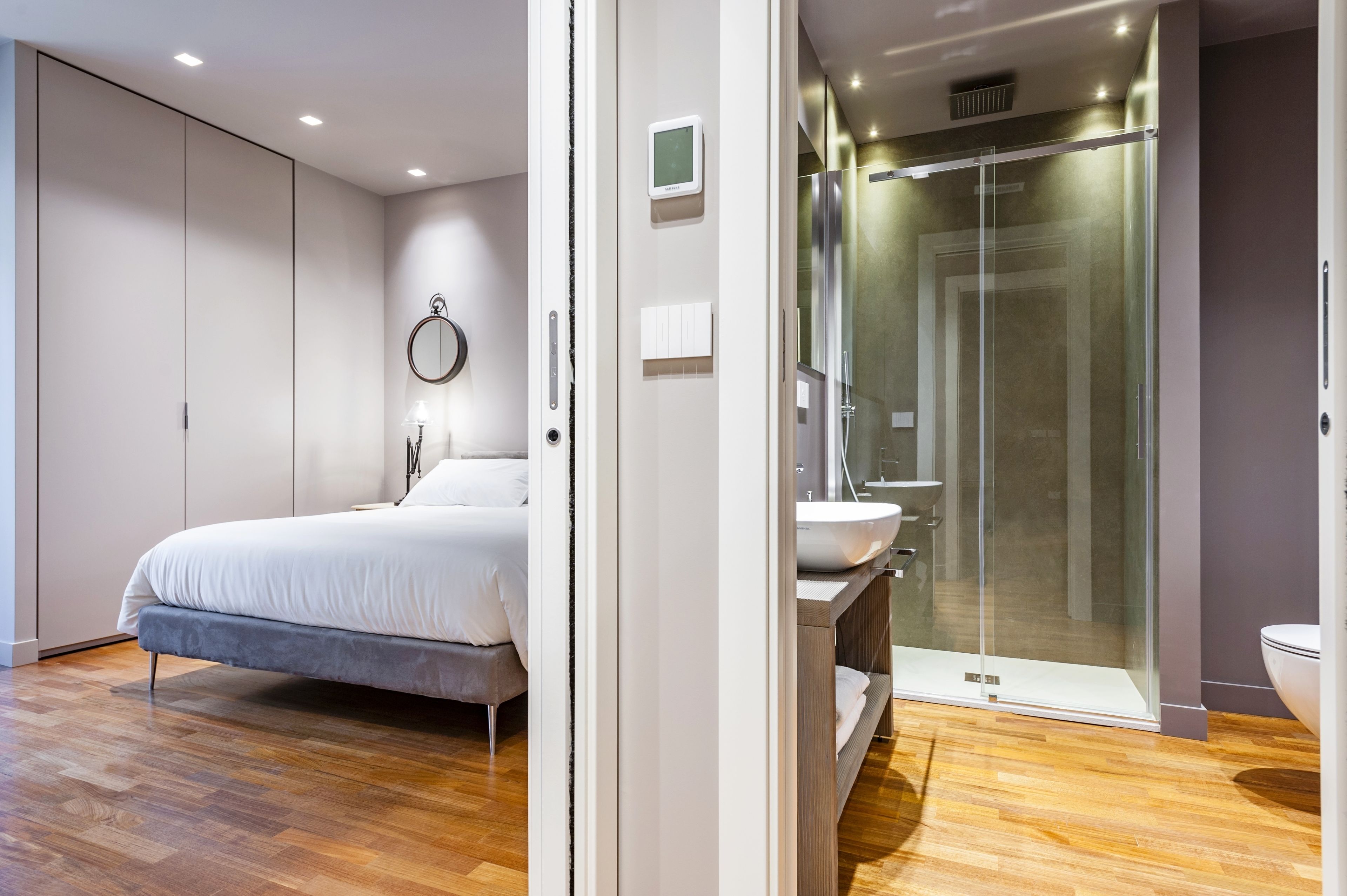 Un dormitorio moderno con una cama, una mesita de noche y un amplio armario.