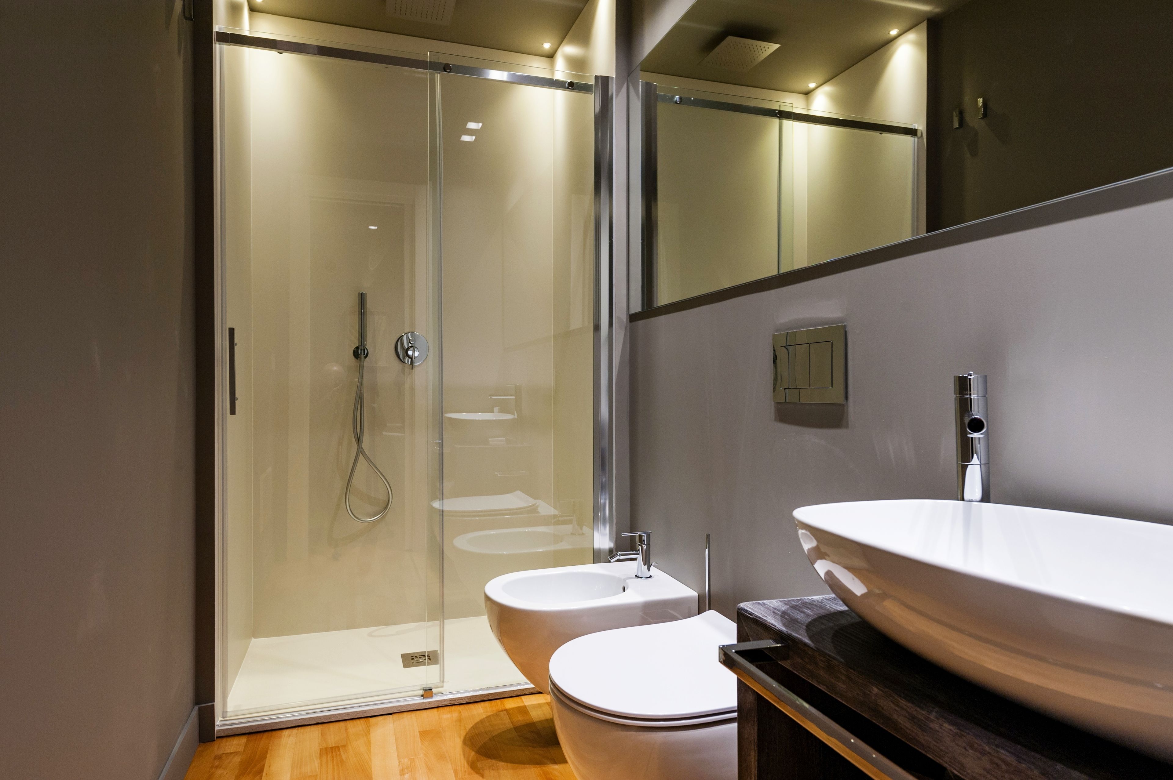 Un bany modern amb dutxa envidriada, un lavabo blanc i un vàter.