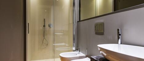 Un bany modern amb dutxa envidriada, un lavabo blanc i un vàter.