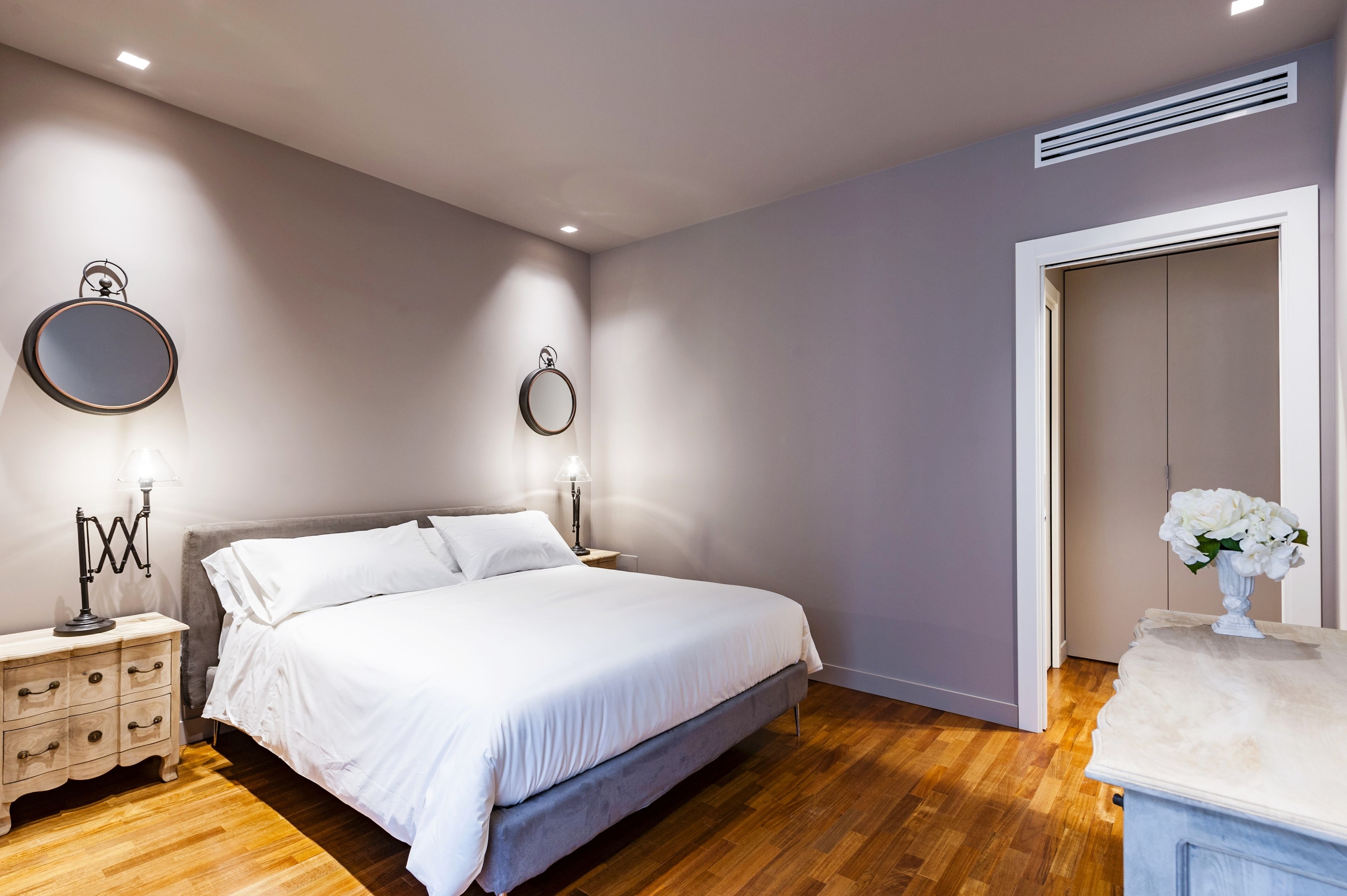 Une chambre à coucher avec un lit, des tables de chevet, un miroir et une commode.