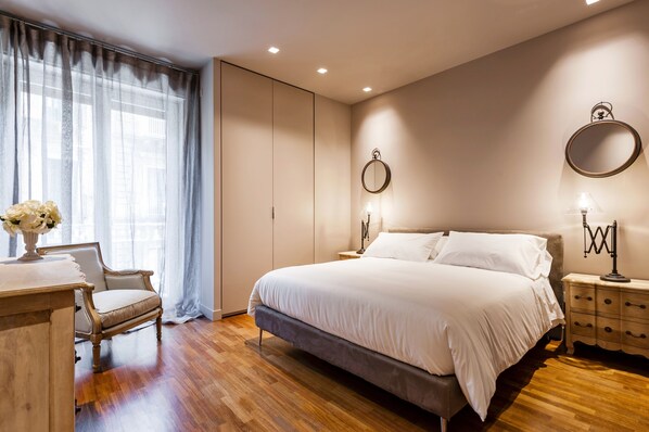 A bedroom with a bed, a desk, a chair, a dresser, and a window with curtains.