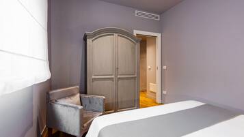 A bedroom with a bed, a wardrobe, and a chair.