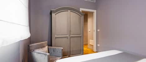 A bedroom with a bed, a wardrobe, and a chair.
