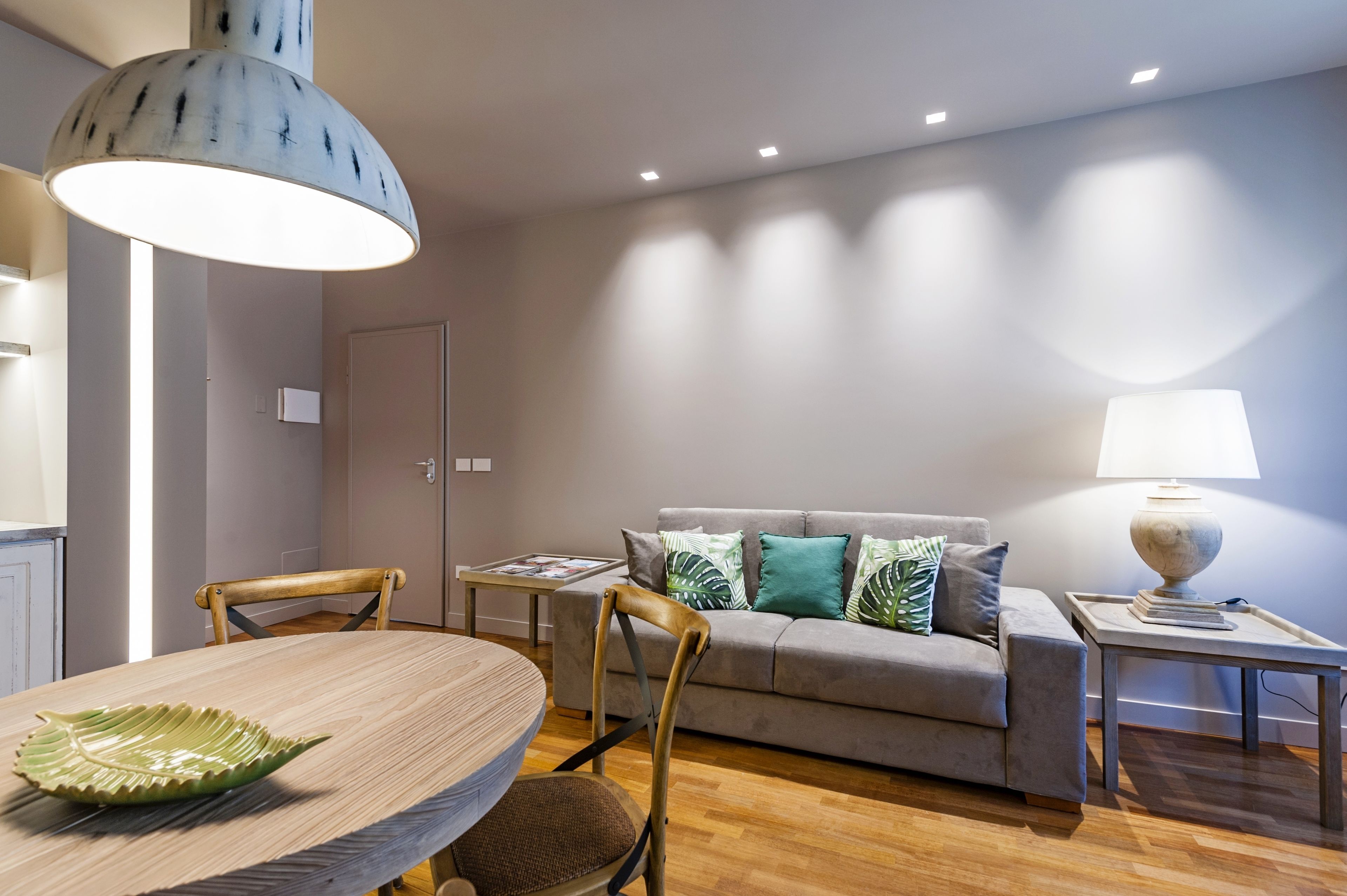 Una sala de estar moderna con sofá, dos sillones, una mesa de comedor y una lámpara.