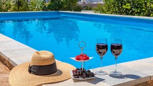 Ein Poolbereich mit Hut, einer Schale Kirschen und zwei Gläsern Rotwein.