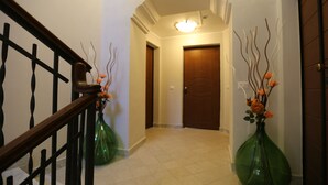 A hallway with a wooden staircase, a door, and two green vases with flowers. - VILLA ROSA - Apartment n. 5 "MYRTLE" (2 beds): (Napoli)